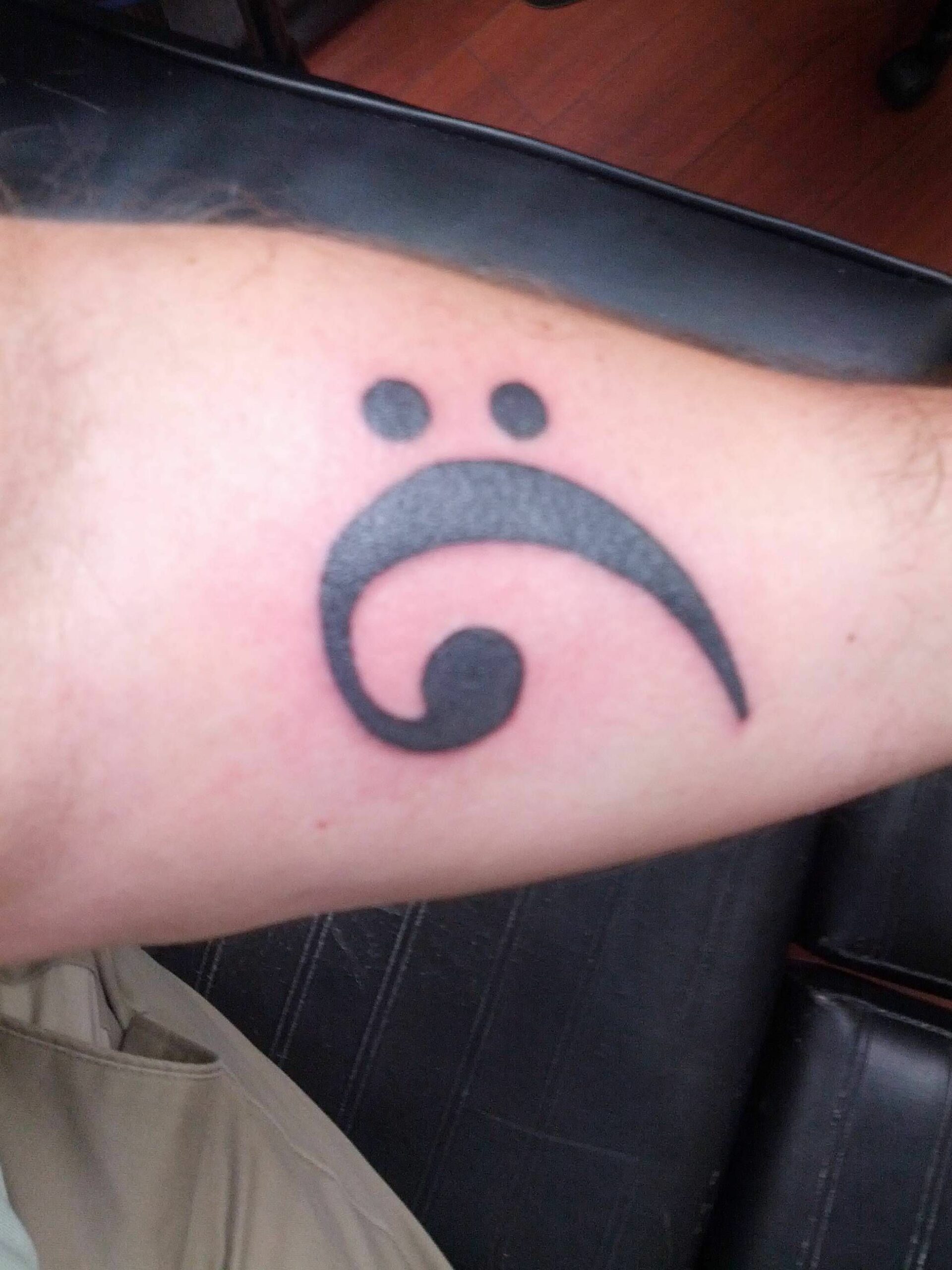 Bass clef tattoo on forearm