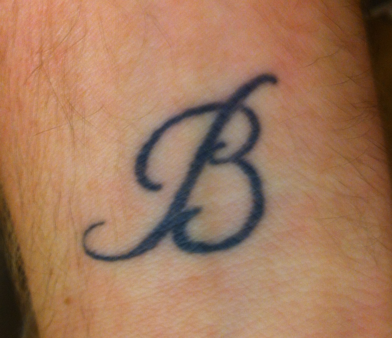 Elegant letter B tattoo on forearm