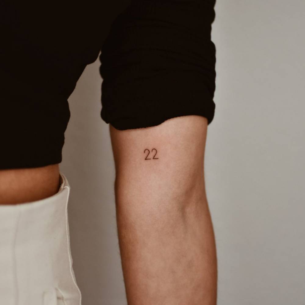 "22" lettering tattoo on the inner arm.