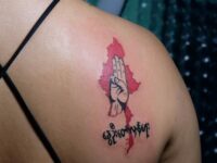 Woman displays a tattoo with a three-finger salute over a map of Myanmar in Yangon